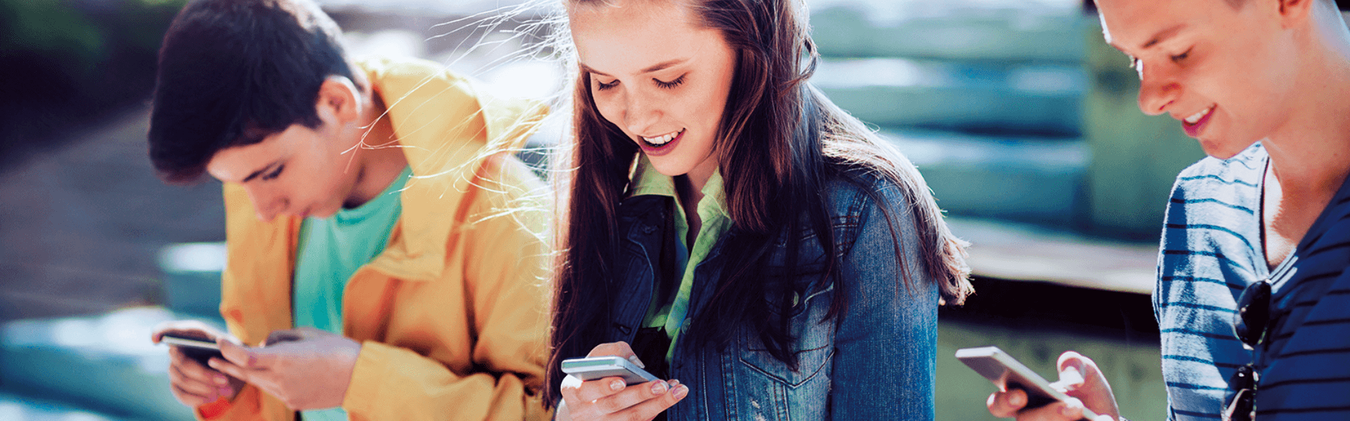 Ein lächelndes Teenager-Mädchen betrachtet seinen Smartphone-BIldschirm